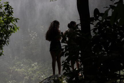 Young women by a waterfall in a tropical forest