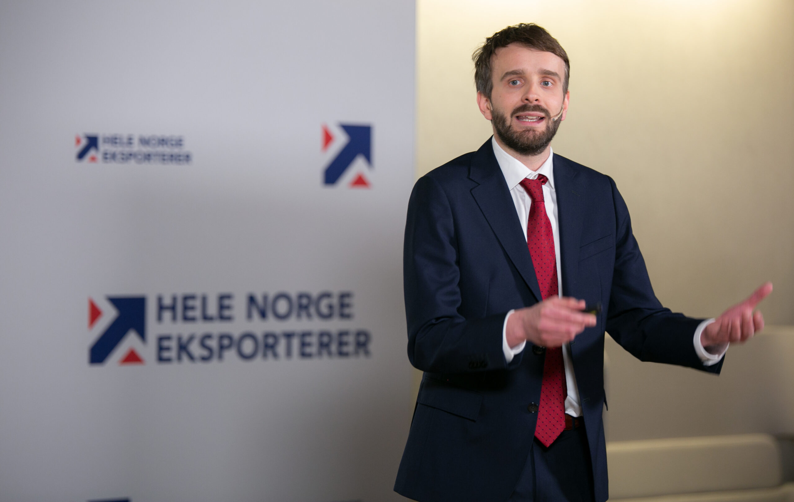 Næringsminister Jan Christian Vestre foran en vegg med logoene til eksportreformen Hele Norge eksporterer