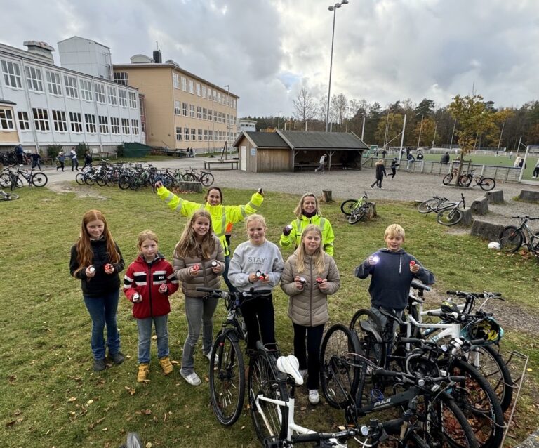 en gruppe med barn bak flere sykler foran en skole