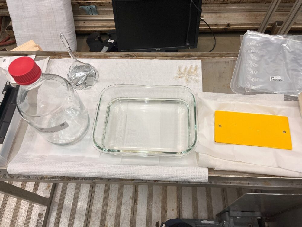 Bildet viser en av komponentene med gult belegg som brukes i havvindpark-industrien (til høyre) og en glassbeholder fylt med sjøvann der utvaskingsprosessen foregår. Foto: SINTEF Ocean AS  