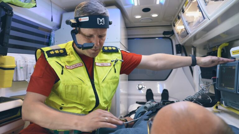 mann utstyrt med sambandsutstyr med pasient inne i en ambulanse