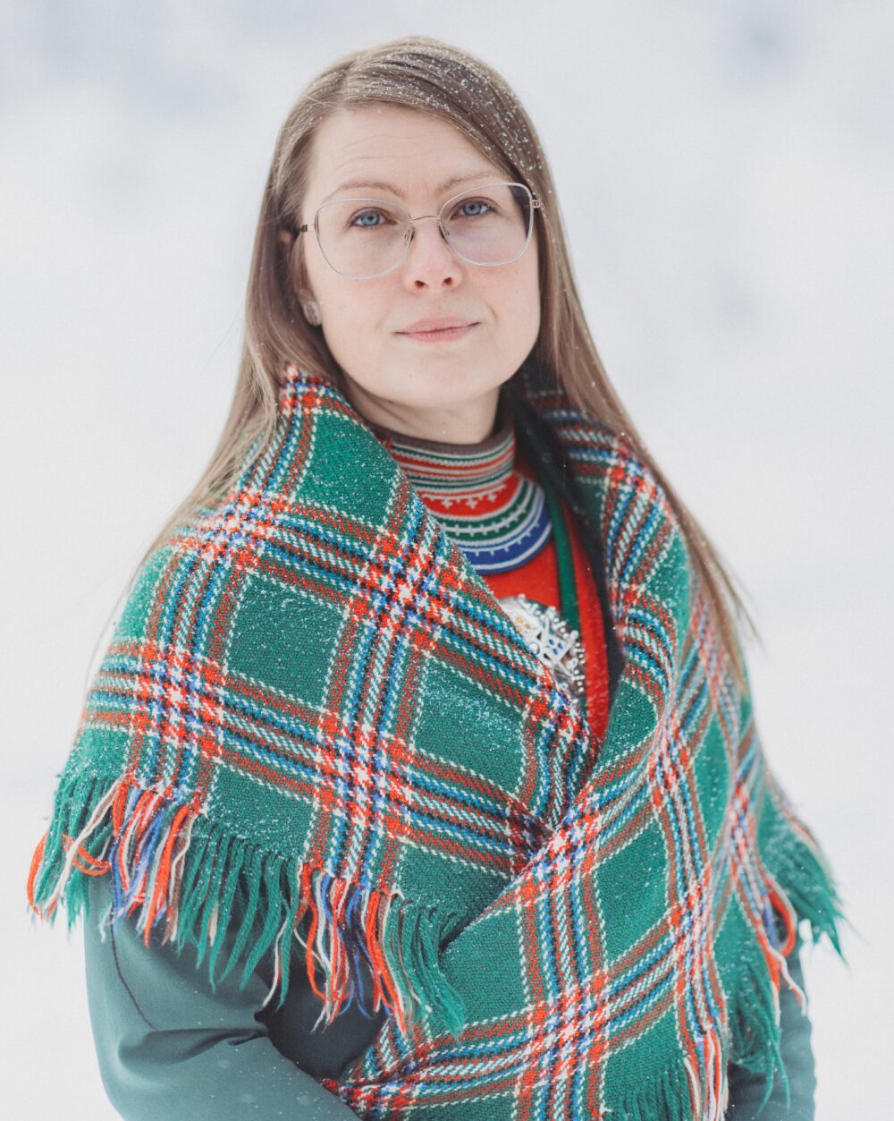 en dame med samiske klær og snø i håret
