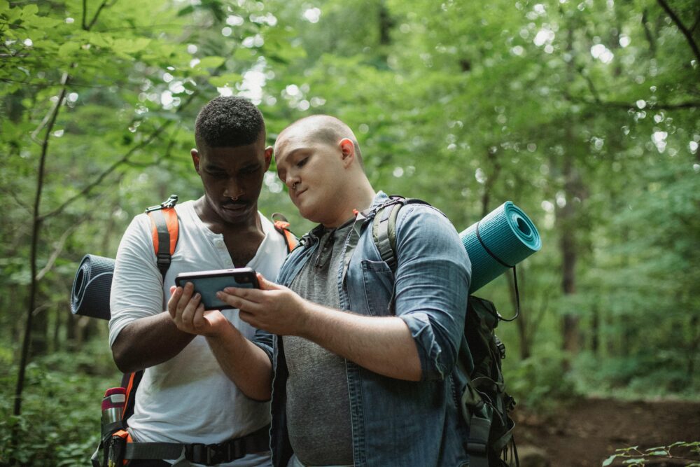 to menn som sjekker en app på telefonen i skogen