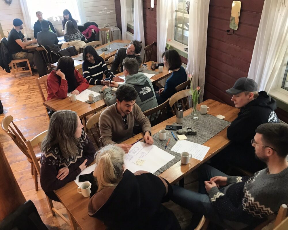 unge mennesker sitter rundt bord og lærer om kulturarv og klimaendringer