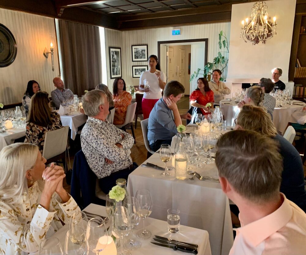 forsamling rundt bord dekket med mat og vin