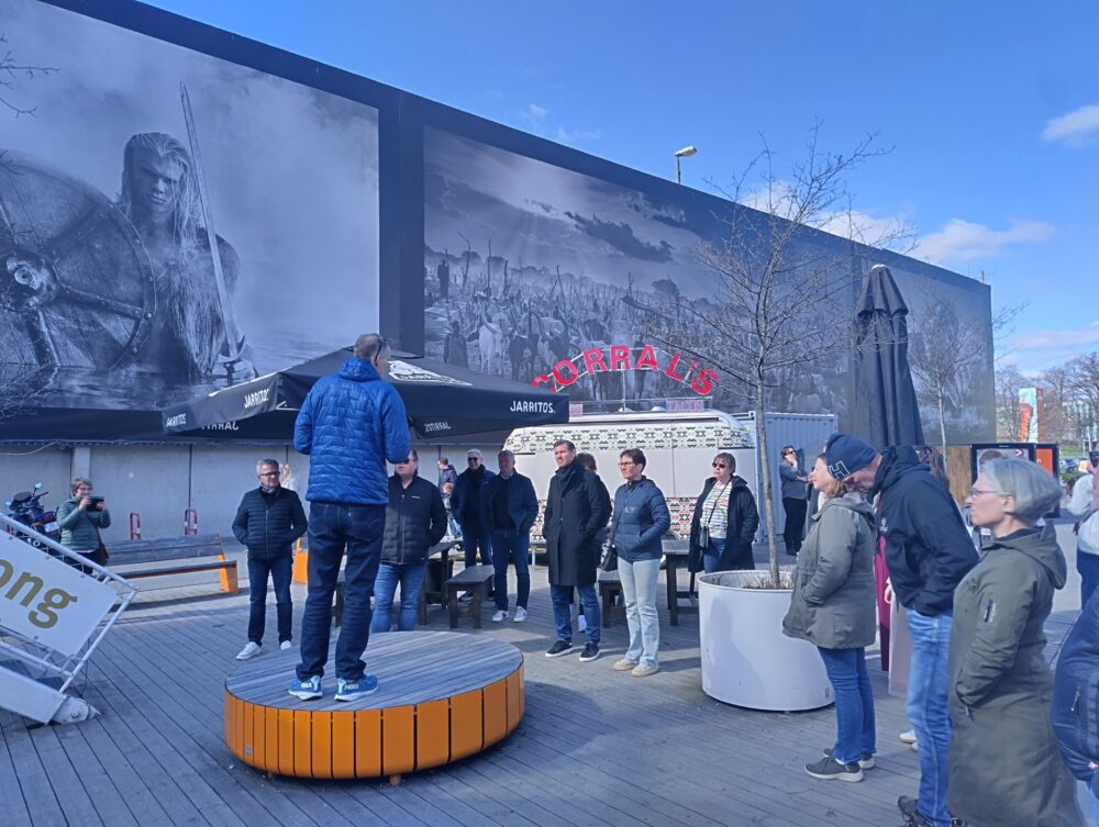 mann som står på en benk og prater foran et publikum - samarbeid over grensen