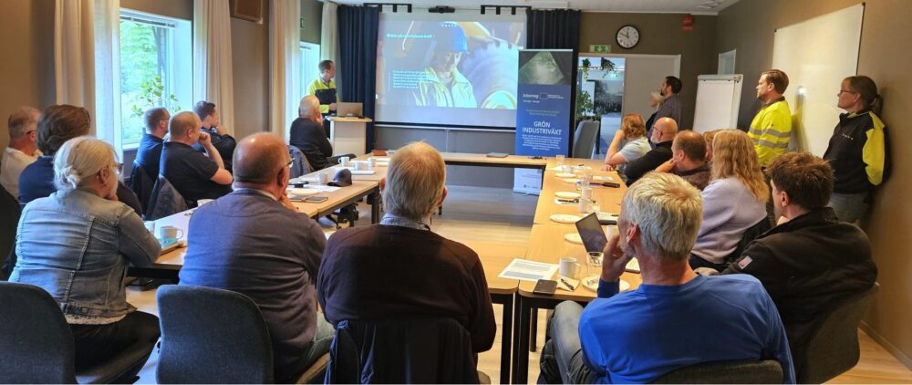 Gruppe mennesker sitter og lytter til en person som holder en presentasjon.