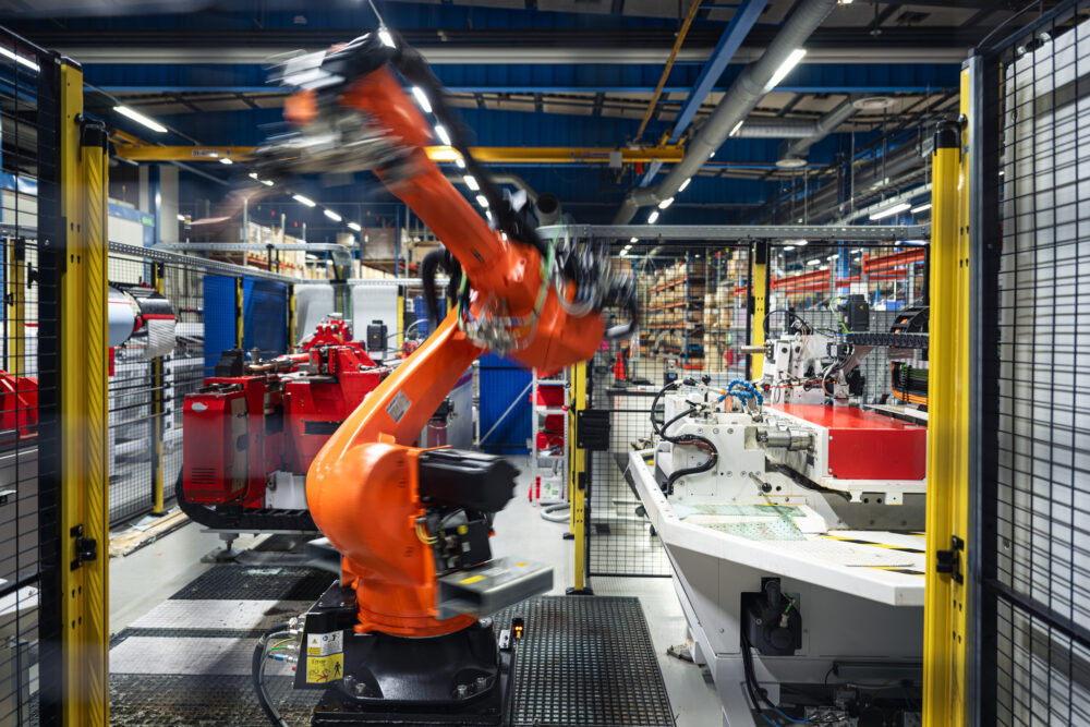 Automatisert industriproduksjon med robotarm i fabrikkmiljø.