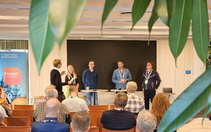 bilde av folk som deltar i en debatt og tilskuere med ryggen til