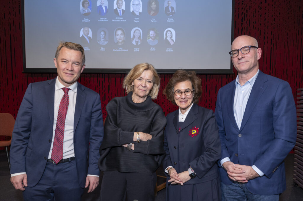 Fire personer på rekke foran scene. To damer i midten, en mann på hver side.