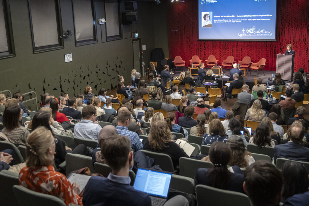 En kvinne taler foran full sal.