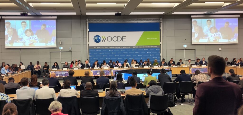 Mange folk rundt ved talerbordet og i salen i OECD